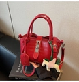 Detail einer roten Handtasche mit Krokodilprägung, Silberverschluss und Pegasus-Anhänger - Rot mit Anhänger