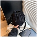 Close-up of black drawstring canvas bucket bag with mesh side pockets and nylon strap - Black