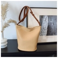 Close-up of woven bucket bag texture with brown leather strap in a minimalist setting - Brown