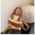 Mini-Strohtasche in Muschelform mit braunem Kunstlederbesatz und Handgriffen in der Hand - Braun