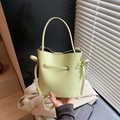 Lime green leather bucket bag with top handle and drawstring in stylish lifestyle shot - Green