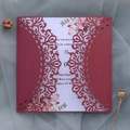 Detalle de invitación de boda calada con láser con elegante diseño floral y fondo suave - Rojo oscuro