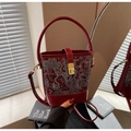 Close-up of vintage wine red bucket bag with traditional phoenix embroidery and gold lock - Burgundy