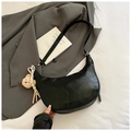 Dettaglio borsa hobo nera a motivo coccodrillo con ciondolo a orso su blazer grigio - Nero