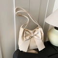 Chic cream straw bucket bag featuring a large leather bow and delicate shoulder strap - Off White