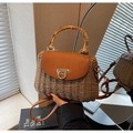 Close-up of woven straw handbag with a bamboo handle and retro vintage metal buckle - Khaki