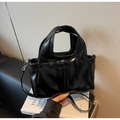 Dettaglio della borsa tote nera lucida con doppi manici e tasche frontali con fibbie - Nero