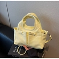 Dettaglio della borsa tote gialla lucida con doppie tasche anteriori su uno sfondo - Giallo