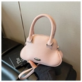 Detailed macro view of pink lychee grain leather shell bag with silver metallic hardware - Pink