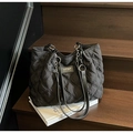Detail of black quilted tote bag with diamond stitching and leather chain shoulder strap - Black