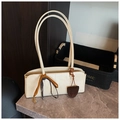 Gros plan du sac baguette en similicuir crème avec pendentif marron sur marbre - Blanc Cassé