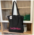 Detail of waterproof nylon tote bag showing pink printed text and cute dog cartoon label - Black