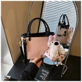 Pink woven bucket bag with black handles and cute plush dog charm detail in a mirror reflection - Pink with Pendant
