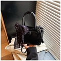 Detail of black textured handbag with silver buckle and black-white polka dot ribbon charm - Black