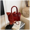 Detail of red patent leather mini bag with polka dot ribbon bow on a silver suitcase - Red