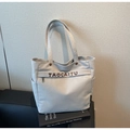 Close-up of canvas tote bag with metal buckles and external zipper pocket on leather sofa - Gray