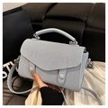Close-up of light blue textured fabric handbag with decorative silver buckles and handle - Blue