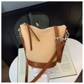 Detail der beigen Strohtasche mit braunem Leder und Silberreißverschluss auf weißem Tisch - Braun