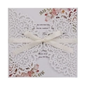 Detail of laser cut ivory wedding invitation with floral pattern and satin ribbon bow - White