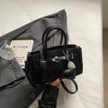 Elegante borsa a mano in pelle nera martellata con dettagli argento e ciondolo - Nero