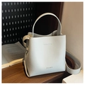 Macro shot of light gray lychee grain leather bucket bag with MACGHEE logo and handle - Grey Blue