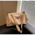 Close-up of beige canvas tote bag with embroidered logo on a black leather bench - Khaki