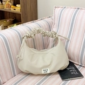 Chic beige ruched dumpling bag with gathered handle and woven label on a soft sofa - Khaki