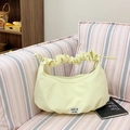 Light yellow crescent handbag with ruched cloud handle and white label on striped sofa - Yellow