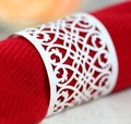 Macro shot of white laser-cut napkin ring with intricate European floral vine patterns - White