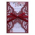 Macro shot of laser-cut burgundy invitation with floral insert and silk ribbon bow - Dark Red