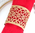 Gros plan d'un rond de serviette doré ajouré au laser sur une serviette rouge - Papier kraft