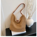 Detailed texture of handmade straw shoulder bag with elegant brown leather strap on white book - Brown