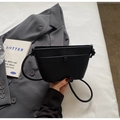 Vista dall'alto di borsa a secchiello in pelle nera con blazer grigio e libro decor - Nero