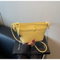 Gros plan d'un sac bandoulière en cuir jaune grainé avec pendentif cœur en argent - Jaune