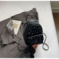 Detail of black mini quilted backpack with silver studs and chain straps on grey blazer - Black
