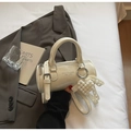 Detalle del bolso cilíndrico blanco crema con cuero brillante y colgante de corazón de perla - Blanco Crema Con Colgante