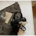 Detalle del bolso boston en charol negro con colgante corazón de perla y encaje - Negro con colgante