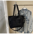 Detail view of large nylon tote bag with front pocket and braided rope zipper pullers - Black