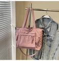 Close-up of pink nylon tote bag with pocket details hanging on a metal rack - Pink
