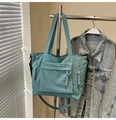 Detail of light blue nylon tote bag with side zippers and woven pulls on a hanger - Blue