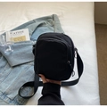 Detalle de bolso bandolera de nailon negro con cremallera sobre una sábana blanca - Negro