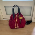 Close-up of red nylon backpack with yellow drawstring, fashion patch and brown dog charm - Red (With Pendant)