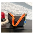 Detail der schwarzen Hobo-Tasche mit orangem Gurt und Anhänger auf Holzoberfläche - Schwarz