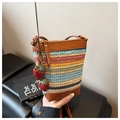 Detail of colorful striped straw bucket bag featuring strawberry charms and leather strap - Brown