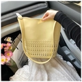 Minimalist light yellow bucket bag with hollow pattern detail on a car seat - Yellow