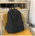 Détail d'un sac à dos noir en nylon avec poche zippée posé sur une chaise en bois - Noir