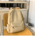 Détail d'un sac à dos d'école minimaliste en nylon beige avec poche sur chaise en bois - Kaki