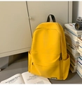 Détail d'un sac à dos en toile jaune vif avec poche zippée dans un décor d'étude chaleureux - Jaune
