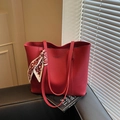 Grand sac cabas rouge en cuir grainé avec foulard décoratif et bandoulières sur un siège - Bordeaux