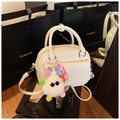 Detailed view of white patent leather handbag with plush monster charm on mirror background - With Charm / Off White
